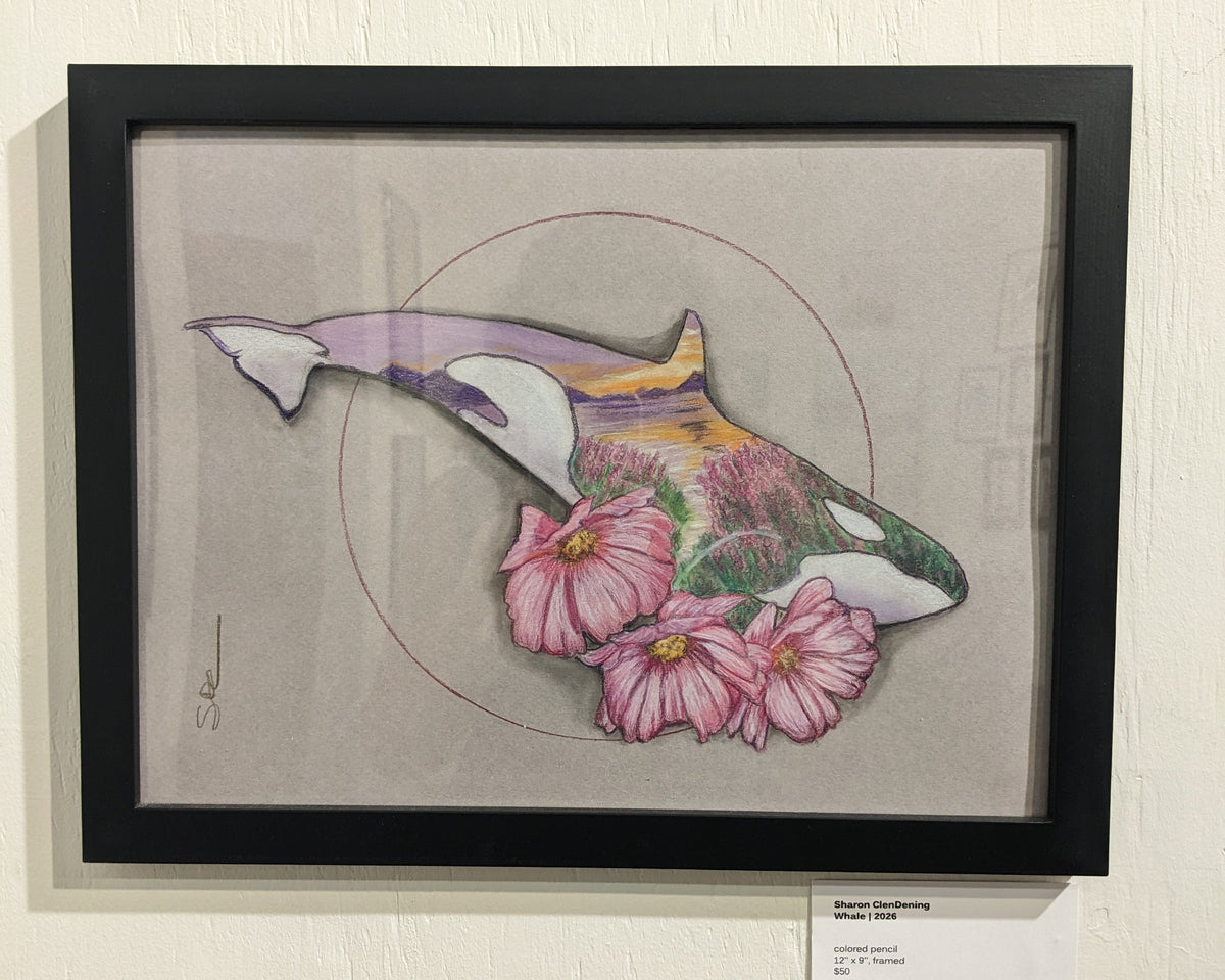 A framed art print featuring a stylized whale with pink flowers, mounted on a textured off-white wall with informational placards below.